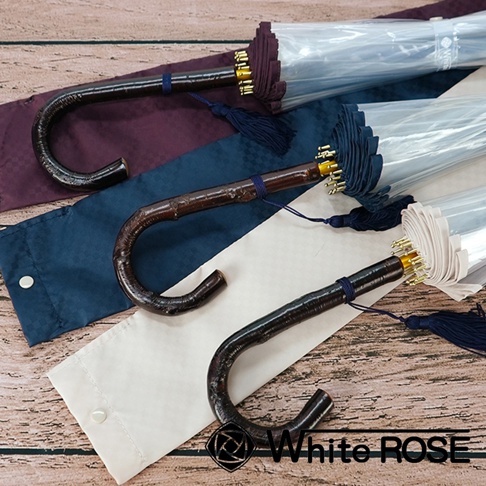 三把職人高級樺木透明傘，傘柄為彎曲的深棕色樺木材質，傘布為透明，配有深藍色流蘇和同色系的傘套，傘套顏色分別為酒紅色、深藍色及米白色。