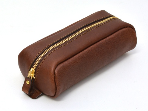 棕色皮革製成的圓角長方形收納筆袋，配有金色拉鍊和皮革拉頭，縫線清晰。