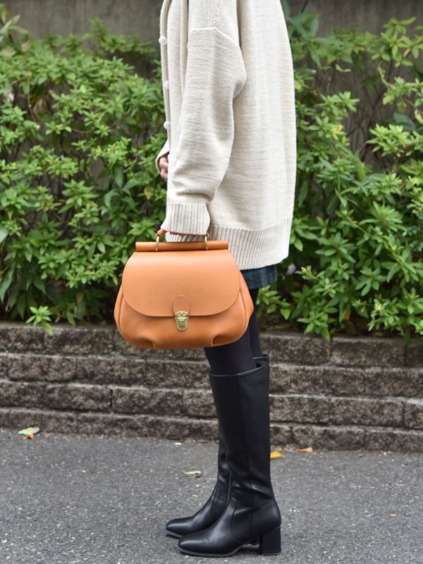 一個棕色皮革迷你後背包，配有金色金屬扣和頂部提把。