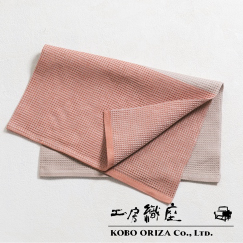 兩塊棉麻混紡鬆餅紋拭巾，一塊為粉橘色，一塊為淺米色，疊放展示。