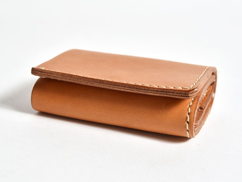 淺棕色皮革三折式迷你短夾，側邊縫線明顯，材質紋理清晰可見。
