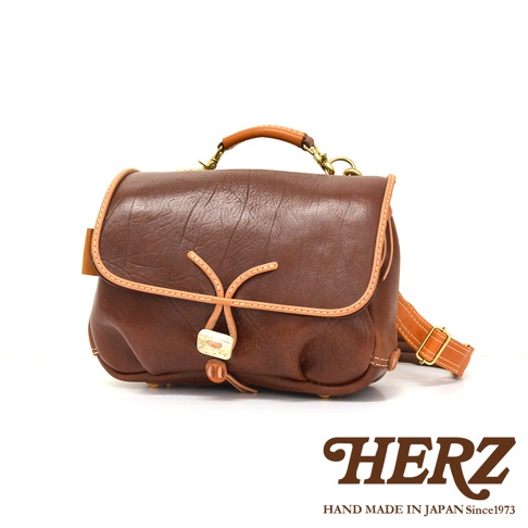 職人手作皮革鹿角扣繩郵差包，深棕色皮革，搭配淺棕色滾邊及束繩，設有提把及可調式肩帶。