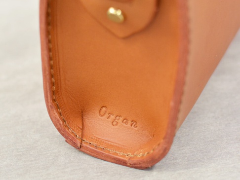 職人手作皮革Organ極簡風拉鍊單肩包 (G-72) M，特寫皮革內裡，壓印有「Organ」字樣，顏色為溫暖的棕褐色，縫線精緻，材質光滑。