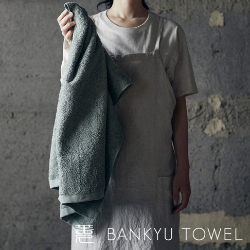 一條灰綠色、觸感蓬鬆的毛巾，由棉質製成，其表面有細緻的紋理。