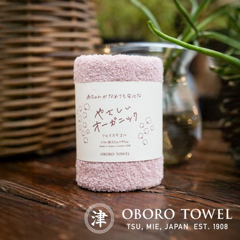 粉色有機棉纖維毛巾，質地柔軟，帶有日文標籤，上面印有品牌名稱「OBORO TOWEL」。