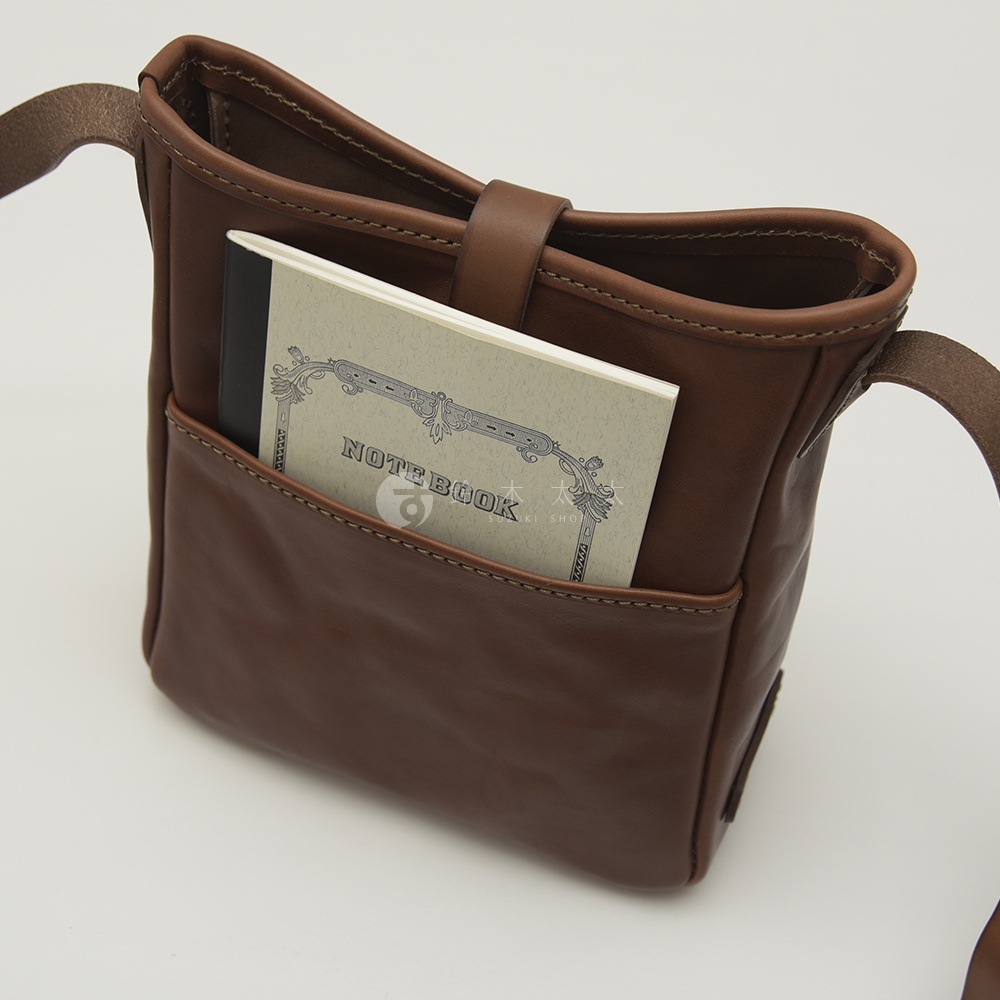 職人手作皮革輕便單肩側背包 CK-91，咖啡色，展現柔軟皮革質感，正面設有方便的置物口袋，一筆記本置於其中。
