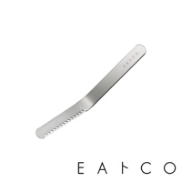 銀色不鏽鋼奶油刀，刀刃一側有鋸齒狀邊緣，另一側有小圓孔，刀柄上方印有「EATCO」字樣。