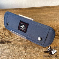 深藍色純棉帆布製成的長方形收納包，帶有銀色按扣和一個黑色方形刺繡布標，上面印有狗的圖案和文字。