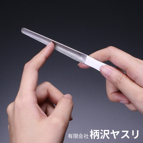 一雙手正以不同的角度展示一把銀色金屬質地的曲面極細高碳鋼銼刀，銼刀表面有細密的紋路，其中一隻手指正輕輕觸碰銼刀的打磨區域。