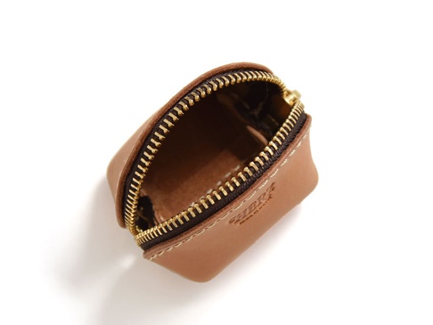淺棕色皮革貝殼造型零錢包，開啟狀態，露出內部，搭配金色拉鍊與白色縫線，品牌壓印於表面。