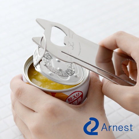 銀色金屬材質的貓咪造型開罐器，正在開啟一罐有黃色內料的罐頭。