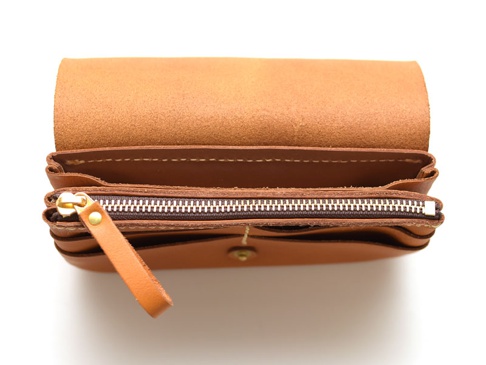 棕色皮革長夾，頂部翻蓋敞開，露出多層次收納空間，內有拉鍊袋，附有皮革拉環和金色拉鍊頭。
