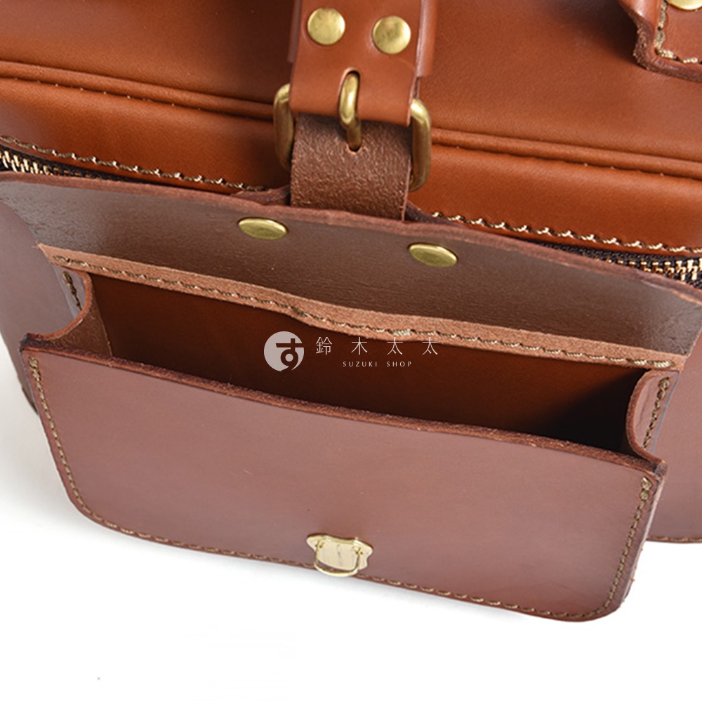 這是一個駝色皮質包，左側有一個打開的口袋，可以看到內部結構，右側有一個金屬扣。