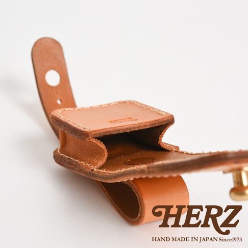 淺棕色皮革製成，附有原子釦開合的腰間小物收納包，帶有穿繩設計，可掛於皮帶上，展現職人手作質感。