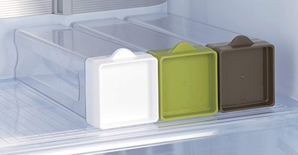 白色、綠色和棕色蓋子的三個透明冰箱收納盒，整齊地放在冰箱架上