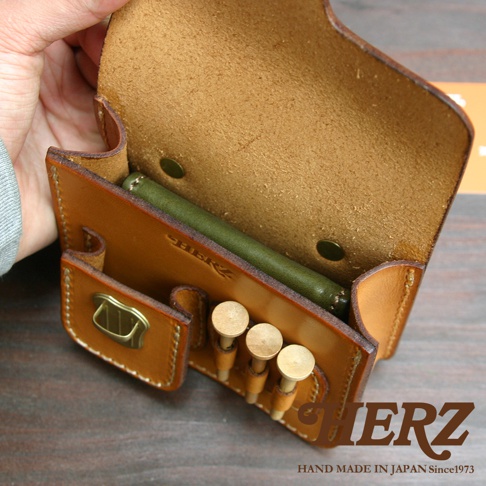 職人手作皮革高爾夫腰包，淺棕色，展示內部空間，可放入綠色長型物體，並有三個黃銅色高爾夫球釘插槽，側面有皮質翻蓋及金屬扣環。