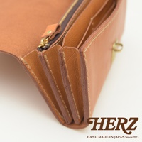 職人手作的淺棕色皮革長夾，展現多卡層的風琴式設計，搭配黃銅拉鍊與扣環，質感細膩。