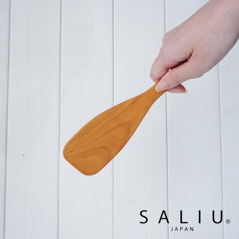YAMASAKURA 山櫻木窄型鍋鏟，淺棕色木質，帶有自然的木紋。鍋鏟呈細長狀，末端為圓弧形，適合攪拌料理。