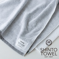 YUKINE 雪中漫步有機棉蓬厚迷你浴巾，圖片顯示兩條浴巾，一條為淺灰色，另一條為白色，皆為100%有機棉材質，表面蓬鬆柔軟，帶有精緻的織紋。
