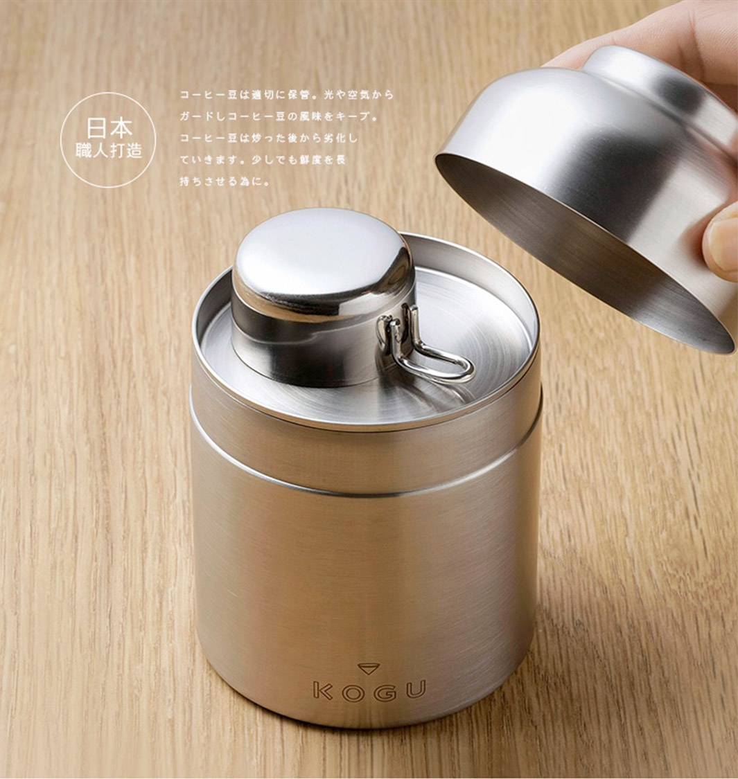 日本製18-8不鏽鋼儲豆罐，罐身為圓柱形，表面呈銀色金屬光澤。罐蓋為圓頂狀，可拆卸。罐身帶有「KOGU」品牌標誌。