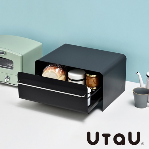 黑色抽屜式收納櫃，櫃內裝有麵包、白色罐子和蜂蜜罐。櫃體為現代簡約設計，底部有可抽出式托盤。