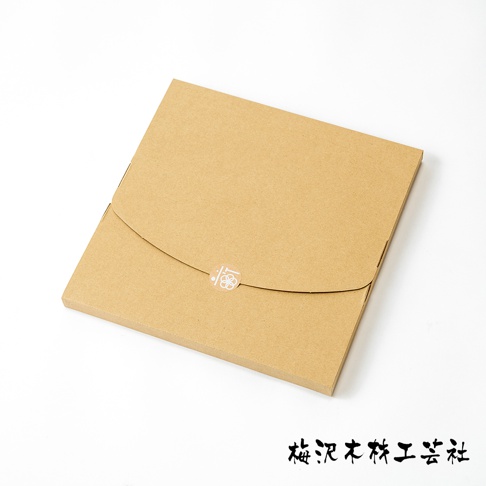 棕色紙盒包裝，盒蓋中央有一個白色圓形貼紙，貼紙上印有白色花朵圖案。