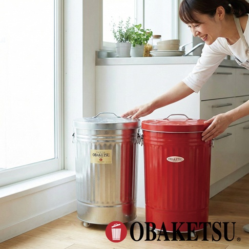OBAKETSU 附輪垃圾桶，一個為銀色鍍鋅鋼材質，另一個為紅色，由一位女士正在觸碰。