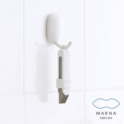 白色萬用去污橡皮擦，掛於白色掛鉤上，橡皮擦主體為白色塑膠，內嵌灰色磨砂材質，末端為斜角設計。