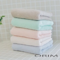 一疊 BISAI 今治浴巾，由上至下分別為淺灰色、薄荷綠、淡粉色、米白色與淺藍色，浴巾材質柔軟，堆疊擺放於白色磁磚背景上。