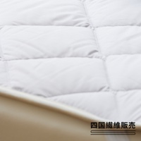 雙人加大尺寸的白色羊毛床墊，表面有菱形格紋縫線，質感柔軟蓬鬆，邊緣為米白色滾邊。