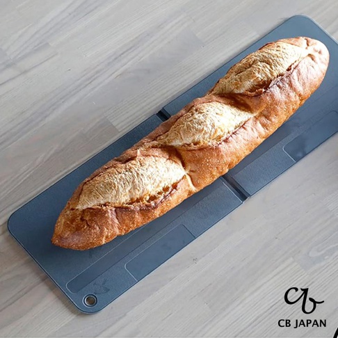 CB JAPAN 的 atomico 系列深灰色可折疊砧板上有法棍麵包