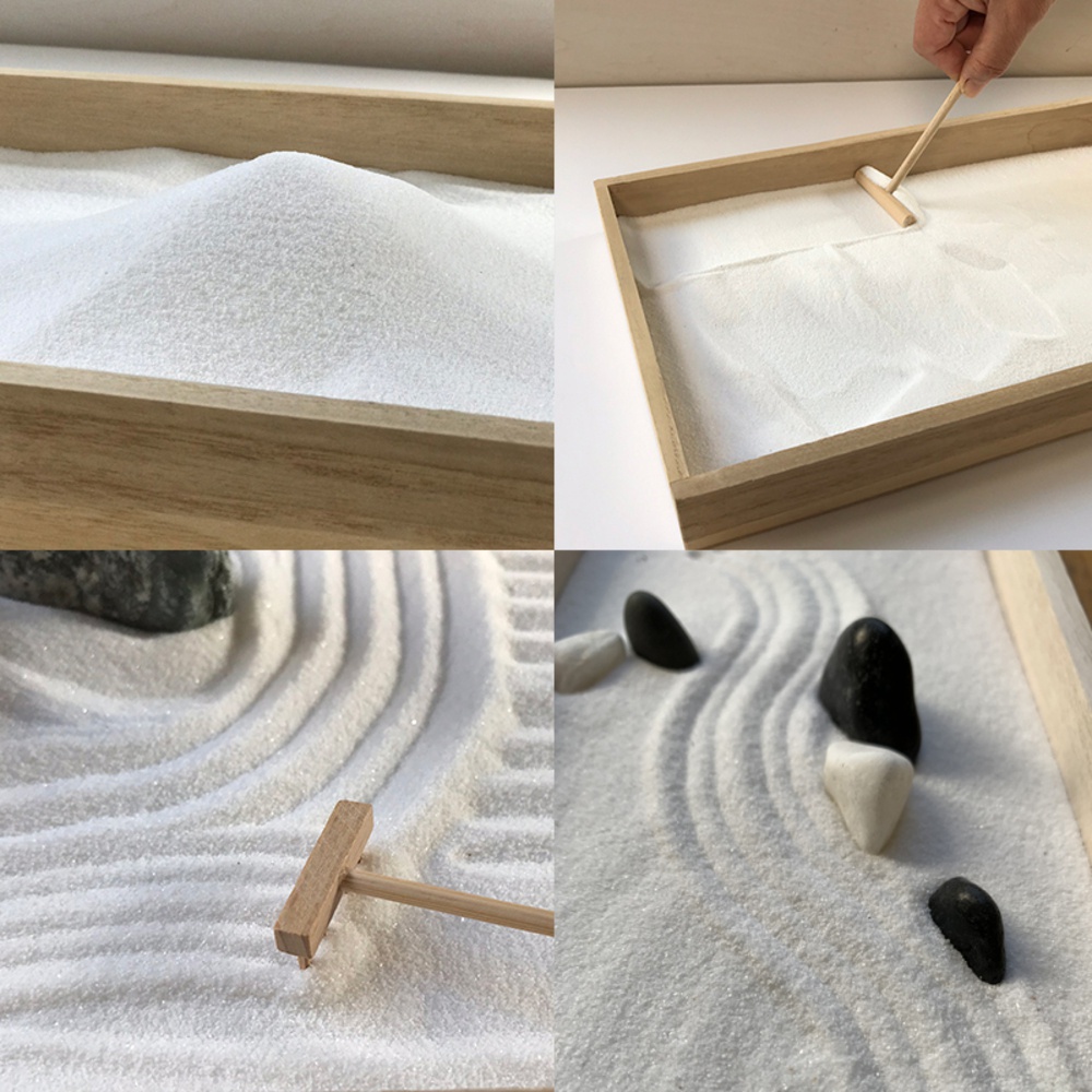 日本枯山水模型，包含淺木紋砂盤、細緻白色砂粒，以及用於梳理砂紋的木製耙子，另有幾顆黑色和白色鵝卵石點綴。