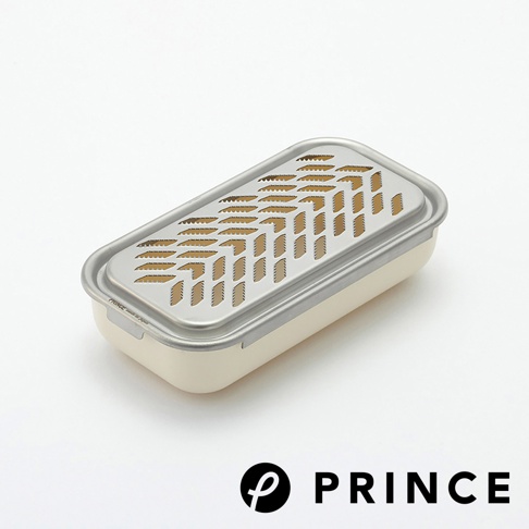 一個米白色的兩用盒，上方覆蓋著不銹鋼網蓋，網蓋上有魚骨狀的磨泥孔和長條狀的切片孔。