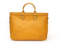 職人手作皮革兩用商務托特包，採用天然棕色皮革製成，設計簡約，配有雙提把和可拆卸肩帶，適合商務及日常使用。包身線條流暢，邊角處有精緻的縫線裝飾，展現精湛工藝。