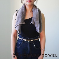 一名女子身穿黑色細肩帶上衣和牛仔褲，脖子上圍著一條灰色毛巾，腰間繫著一條米色皮帶，手腕上戴著粉色手鍊。