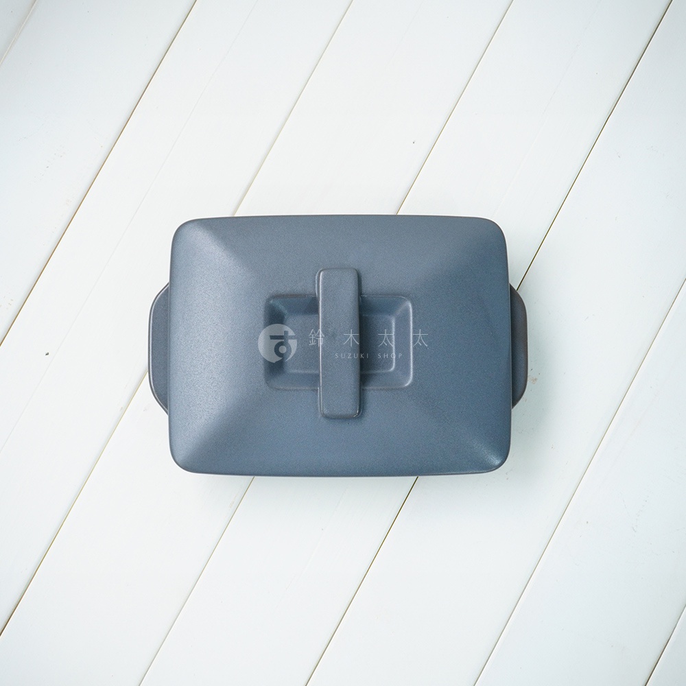 深灰色陶製長方形烤盤，帶有附蓋和把手，平底設計，置於白色木紋背景上。