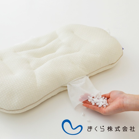 淺米色調節枕，表面為紋理織物，帶有凹凸條紋。枕頭一側有一個網狀開口，露出裝有大量白色圓柱形顆粒的手。