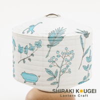 白色紙質提燈，繪有藍色線條的植物圖案，包括葉子、漿果和蕨類植物，以及一隻小豬和一隻猴子。提燈頂部有金屬提環，底部為木質支架。