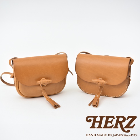 兩款職人手作皮革流蘇側背包，皆為淺棕色，採用天然皮革材質，設計簡約，配有皮革流蘇和獨特的旋轉扣。