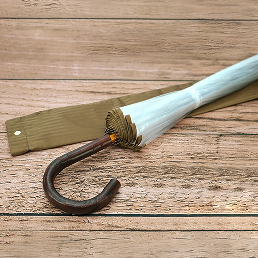 職人高級樺木透明傘，傘面為透明材質，傘柄為深棕色彎曲樺木，配有同色系的收納套，整體展現簡約質感。