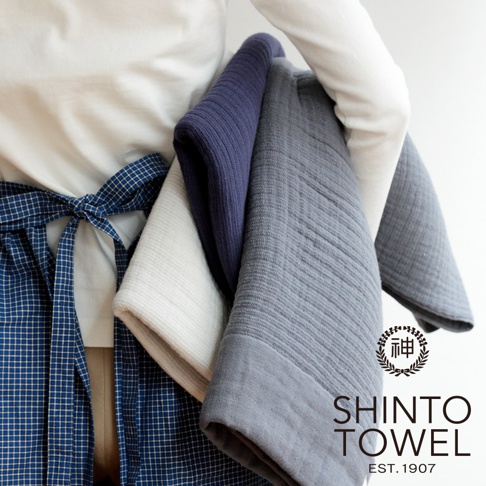 三條 INNER PILE 雙面紗布輕質浴巾，分別為深藍色、淺灰色和白色，展示其柔軟的紗布材質和紋理。