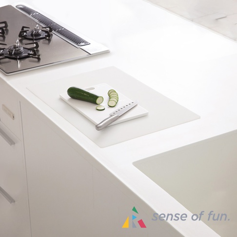 白色方形耐高溫料理台保護墊，上面放著白色砧板，砧板上有小黃瓜和一把銀色刀具。