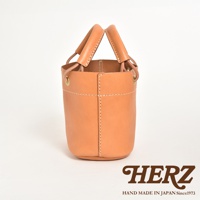 淺棕色皮革製成的手提午餐袋，圓筒狀造型，大開口設計，配有雙提把，側邊有縫線裝飾。