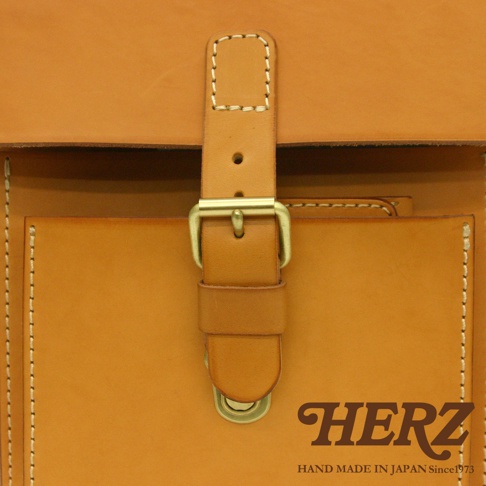 職人手作皮革單肩兩用小方包 A-10，展示為淺棕色皮革材質，帶有縫線細節與黃銅色金屬釦具，下方印有品牌 Logo。