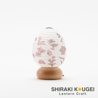 一個蛋形白色紙質提燈，燈罩上印有粉色兔子、松鼠、刺蝟及花卉圖案，燈座為圓形淺木色木製底座。