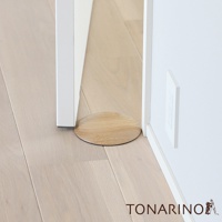 圓形天然實木門擋，淺木色，表面有木紋，底部為防滑材質，放置於白色門框與木質地板之間。