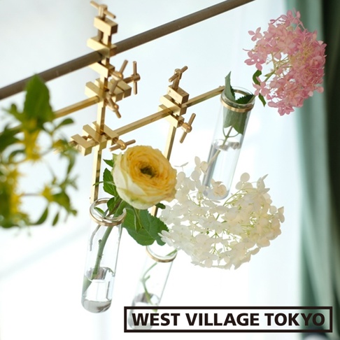 黃銅支架夾著多個玻璃試管花器，內插有黃色、白色和粉紅色的花朵，以及綠葉。