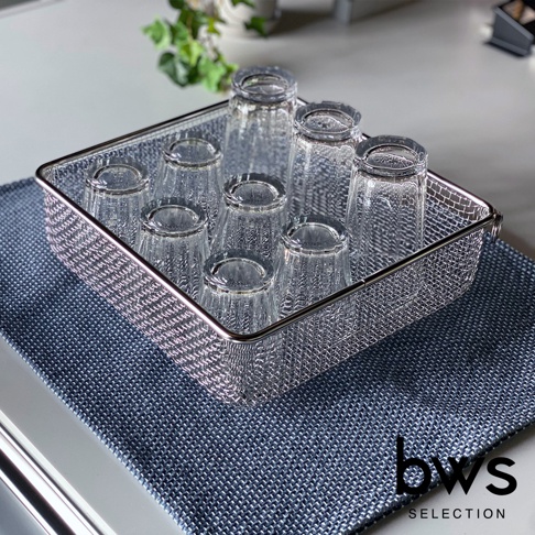 不鏽鋼製的方形瀝水籃，籃身為網狀結構，籃邊有圓潤的不鏽鋼邊框，籃內放置了七個透明的玻璃杯，杯子倒置於籃中，瀝水籃下方墊著深藍色的紋路布墊。