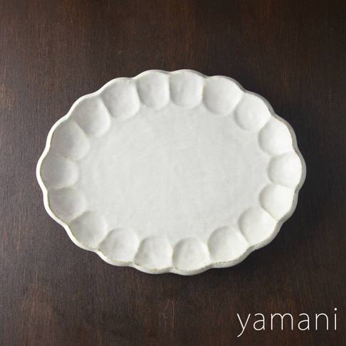 一個白色、橢圓形、帶有壓花花瓣邊緣的陶瓷料理盤，尺寸約為 30 公分。