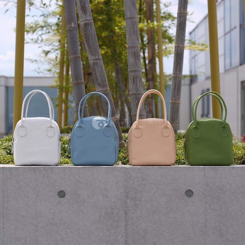 四款皮革手提包，分別為白色、淺藍色、裸膚色和綠色，皆為貝殼造型，款式簡潔。